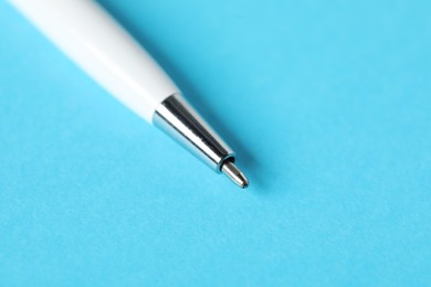 Photo of One ballpoint pen on light blue background, macro view. Space for text