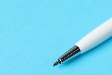 Photo of One ballpoint pen on light blue background, macro view. Space for text
