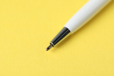Photo of One ballpoint pen on yellow background, macro view. Space for text