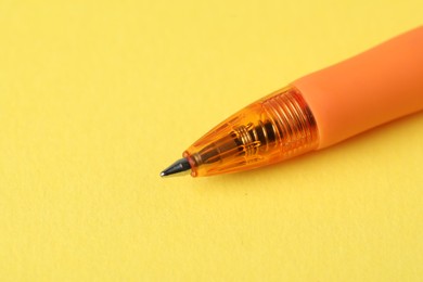 Photo of One ballpoint pen on yellow background, macro view. Space for text