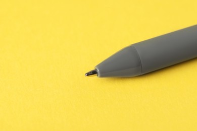 Photo of One ballpoint pen on yellow background, macro view. Space for text