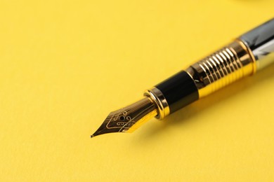 Photo of One fountain pen on yellow background, macro view. Space for text