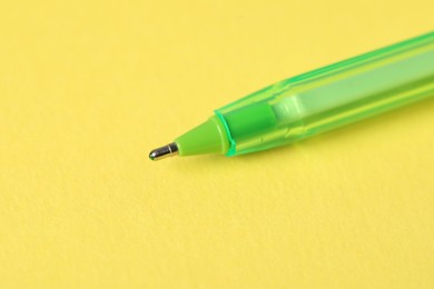 Photo of One ballpoint pen on yellow background, macro view. Space for text