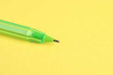 Photo of One ballpoint pen on yellow background, macro view. Space for text