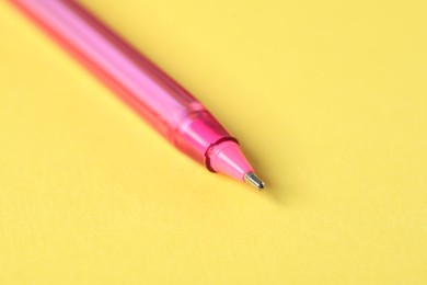 Photo of One ballpoint pen on yellow background, macro view. Space for text