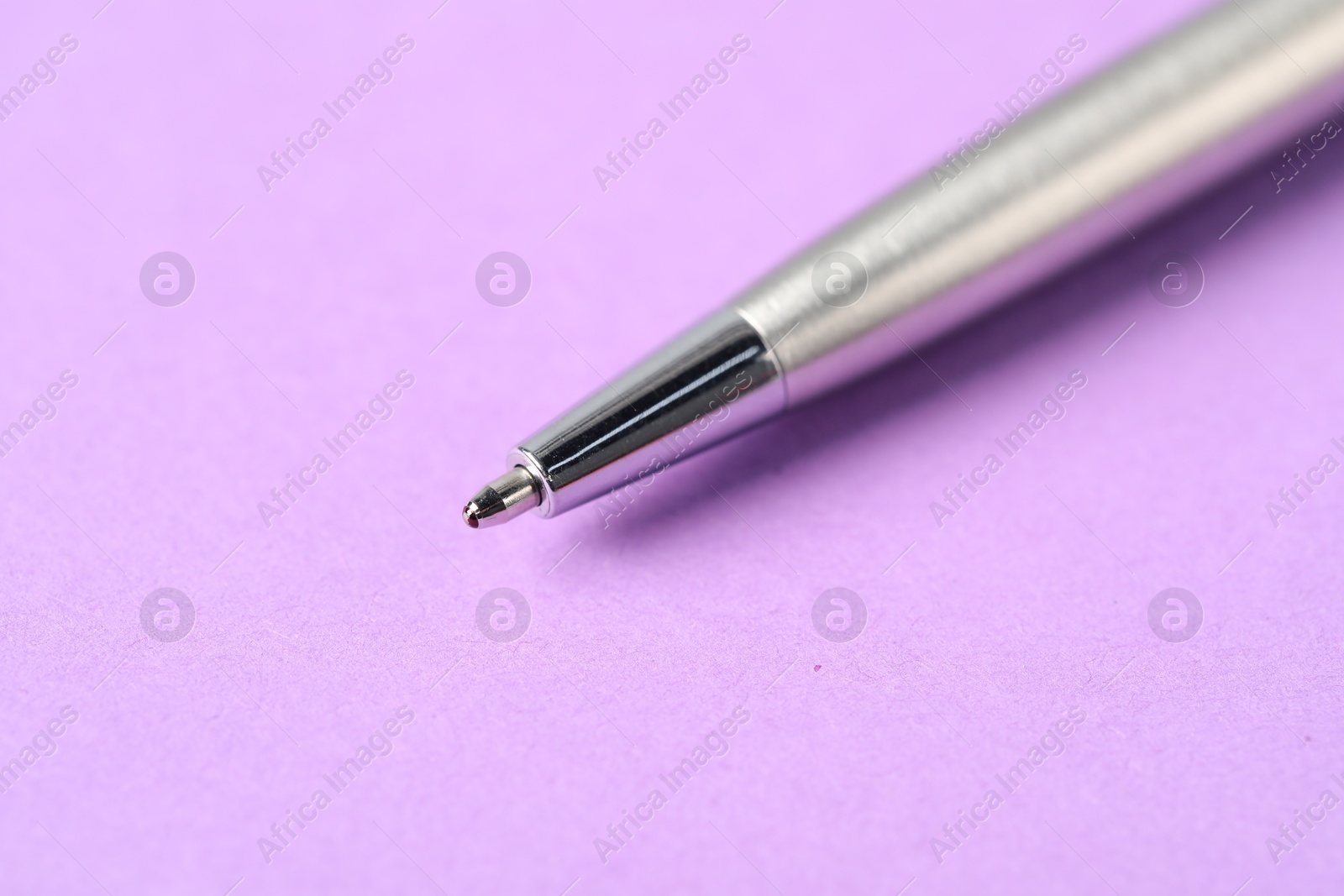 One stylish pen on violet background, macro view. Space for text Photo of One stylish pen on violet background, macro view. Space for text