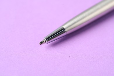 Photo of One stylish pen on violet background, macro view. Space for text