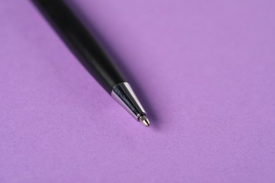 Photo of One stylish pen on violet background, macro view. Space for text