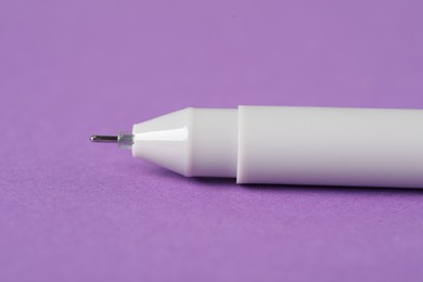 Photo of One stylish pen on violet background, macro view