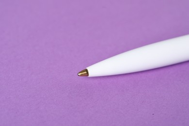 Photo of One stylish pen on violet background, macro view. Space for text