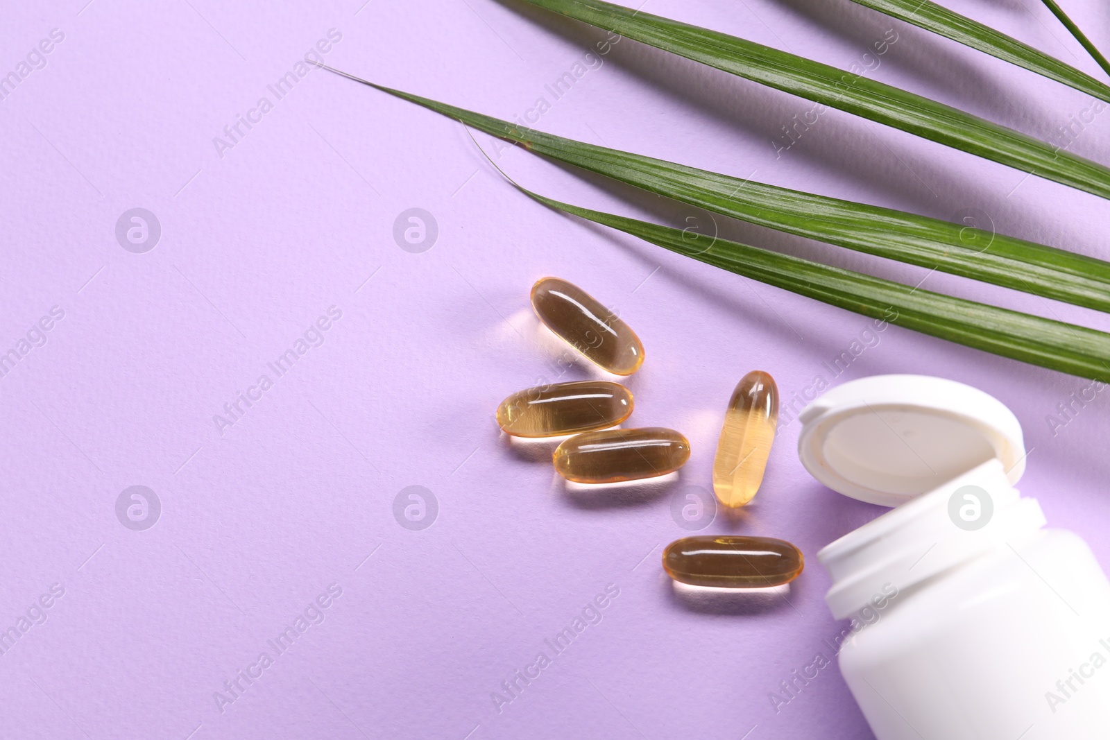 Collagen capsules and leaves on violet background, flat lay. Space for text Photo of Collagen capsules and leaves on violet background, flat lay. Space for text