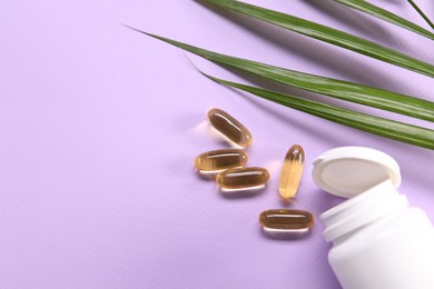 Photo of Collagen capsules and leaves on violet background, flat lay. Space for text