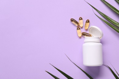 Photo of Collagen capsules and leaves on violet background, flat lay. Space for text