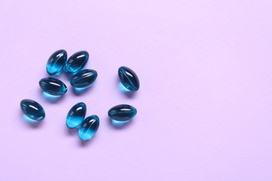 Photo of Collagen capsules on violet background, flat lay. Space for text