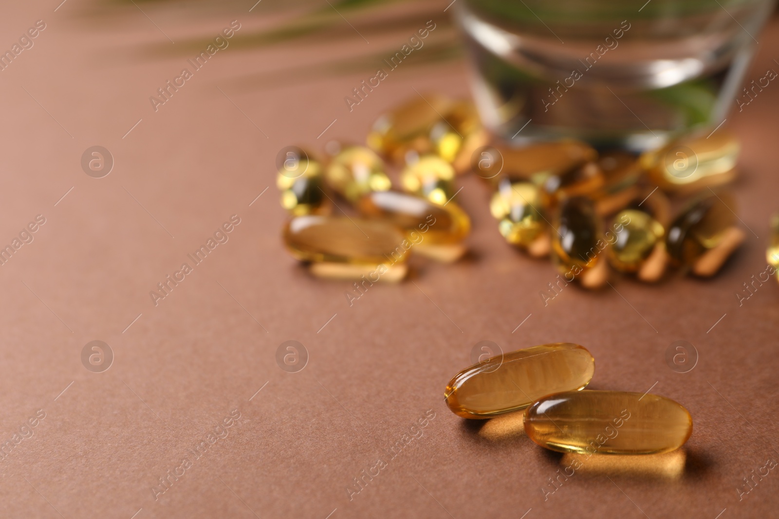 Collagen capsules and water on brown background, closeup. Space for text Photo of Collagen capsules and water on brown background, closeup. Space for text