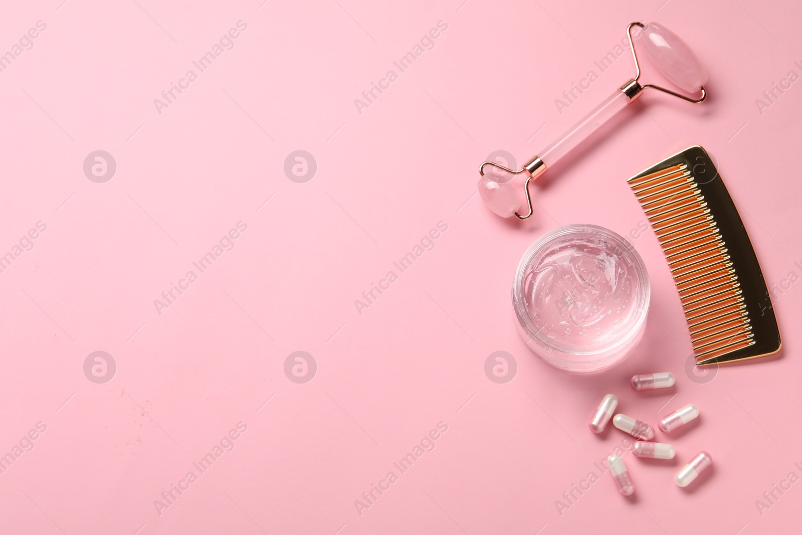 Collagen capsules, gel, comb and face roller on pink background, flat lay. Space for text Photo of Collagen capsules, gel, comb and face roller on pink background, flat lay. Space for text