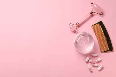 Photo of Collagen capsules, gel, comb and face roller on pink background, flat lay. Space for text