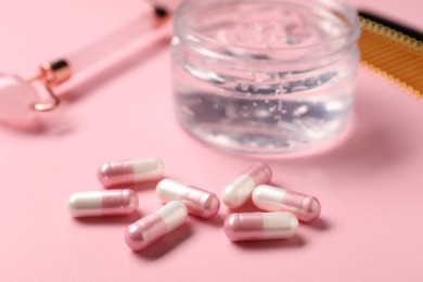 Photo of Collagen capsules, gel and face roller on pink background, closeup
