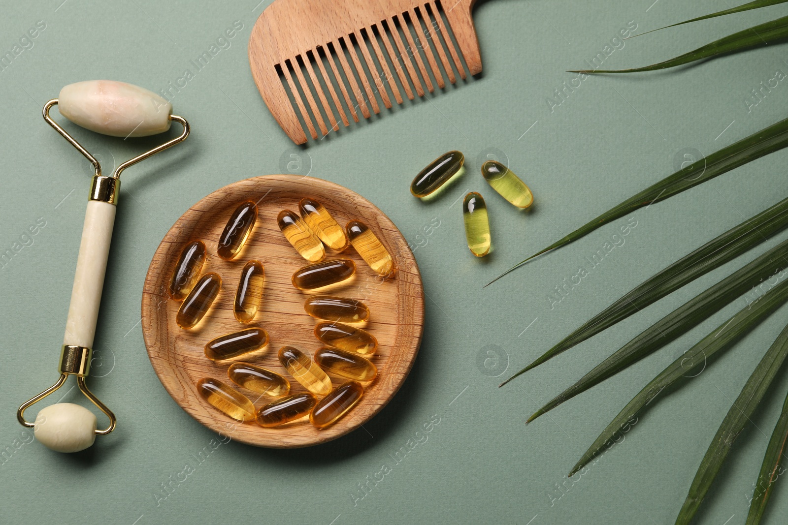 Collagen capsules, comb, face roller and leaves on light green background, flat lay Photo of Collagen capsules, comb, face roller and leaves on light green background, flat lay