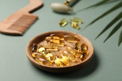 Photo of Collagen capsules, comb and leaves on light green background, closeup