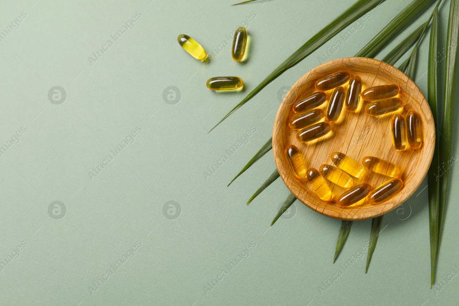 Collagen capsules and leaves on light green background, flat lay. Space for text Photo of Collagen capsules and leaves on light green background, flat lay. Space for text