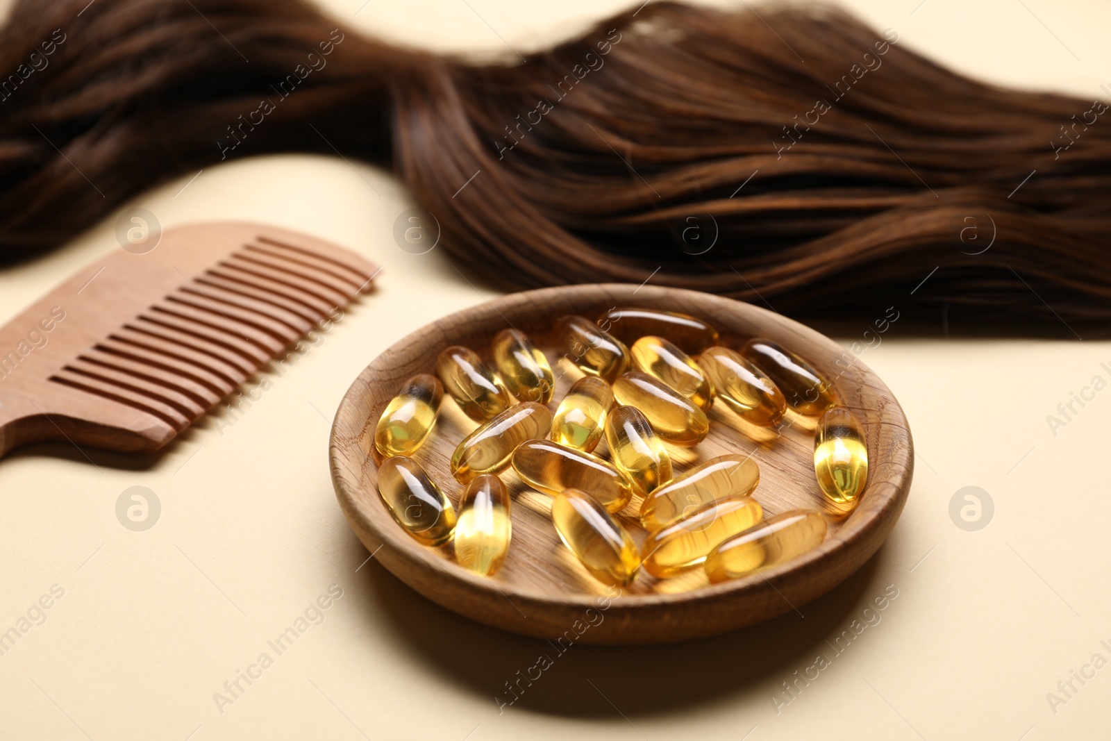 Collagen capsules, hair lock and comb on beige background, closeup Photo of Collagen capsules, hair lock and comb on beige background, closeup