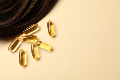 Photo of Collagen capsules and hair lock on beige background, flat lay. Space for text