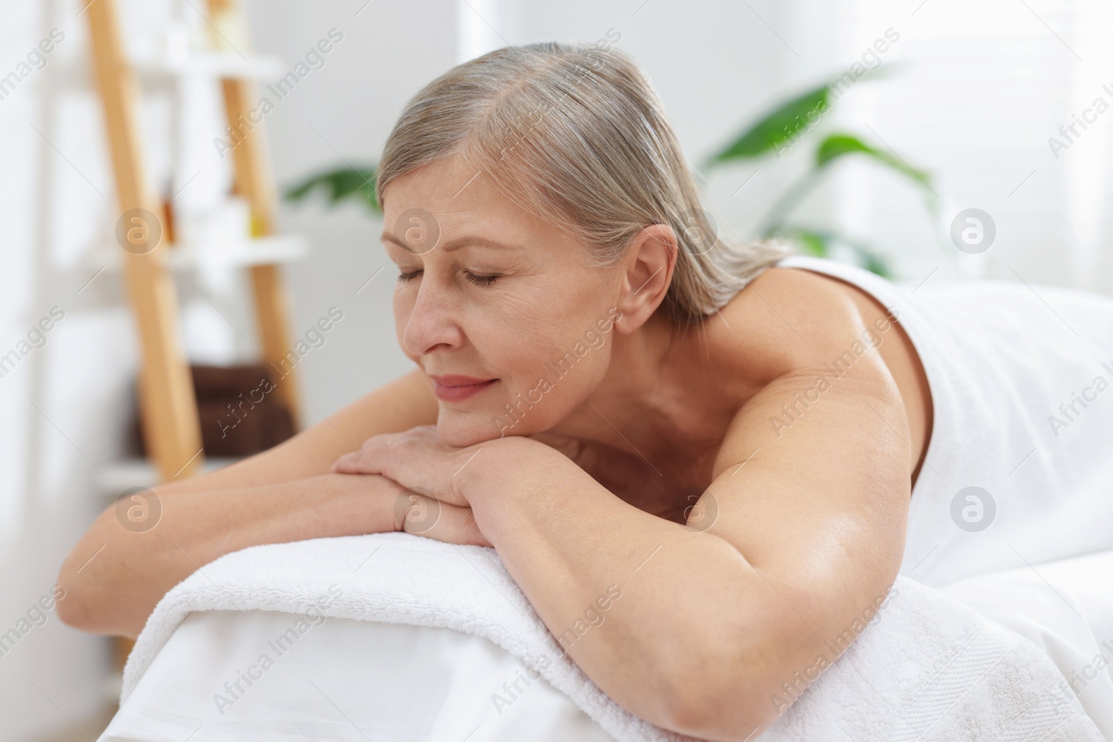 Senior woman relaxing on massage couch in spa salon Photo of Senior woman relaxing on massage couch in spa salon