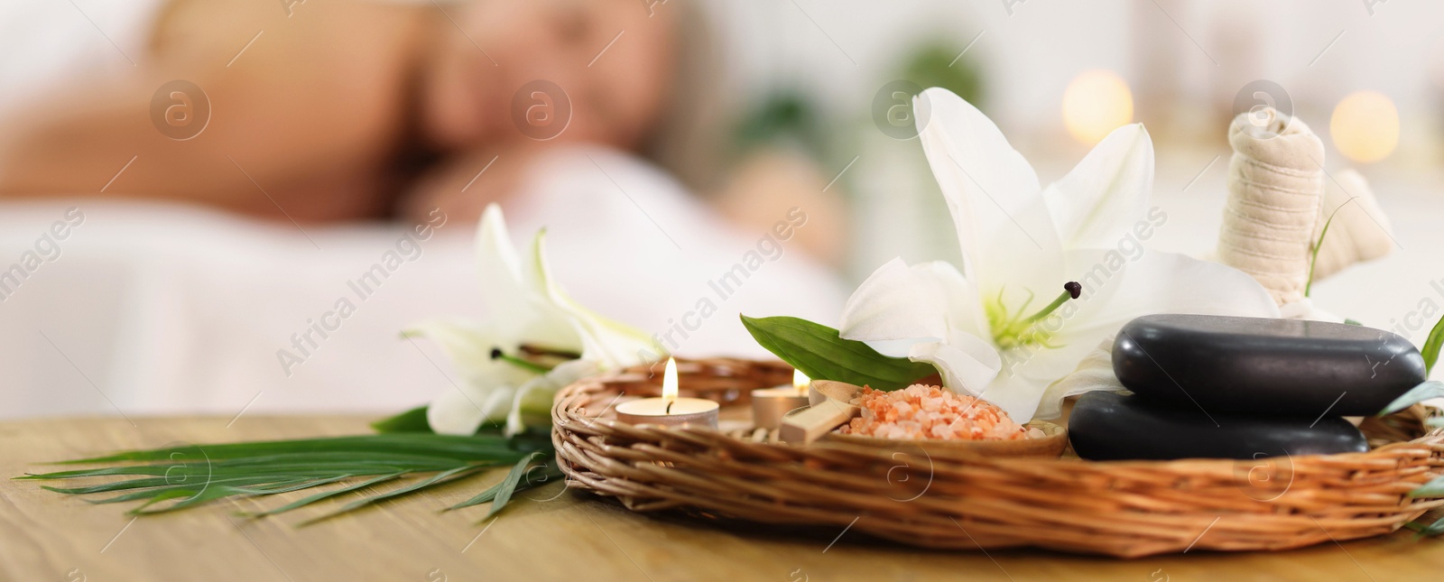 Senior woman relaxing on massage couch indoors, selective focus. Different spa products and lily flowers on table Photo of Senior woman relaxing on massage couch indoors, selective focus. Different spa products and lily flowers on table