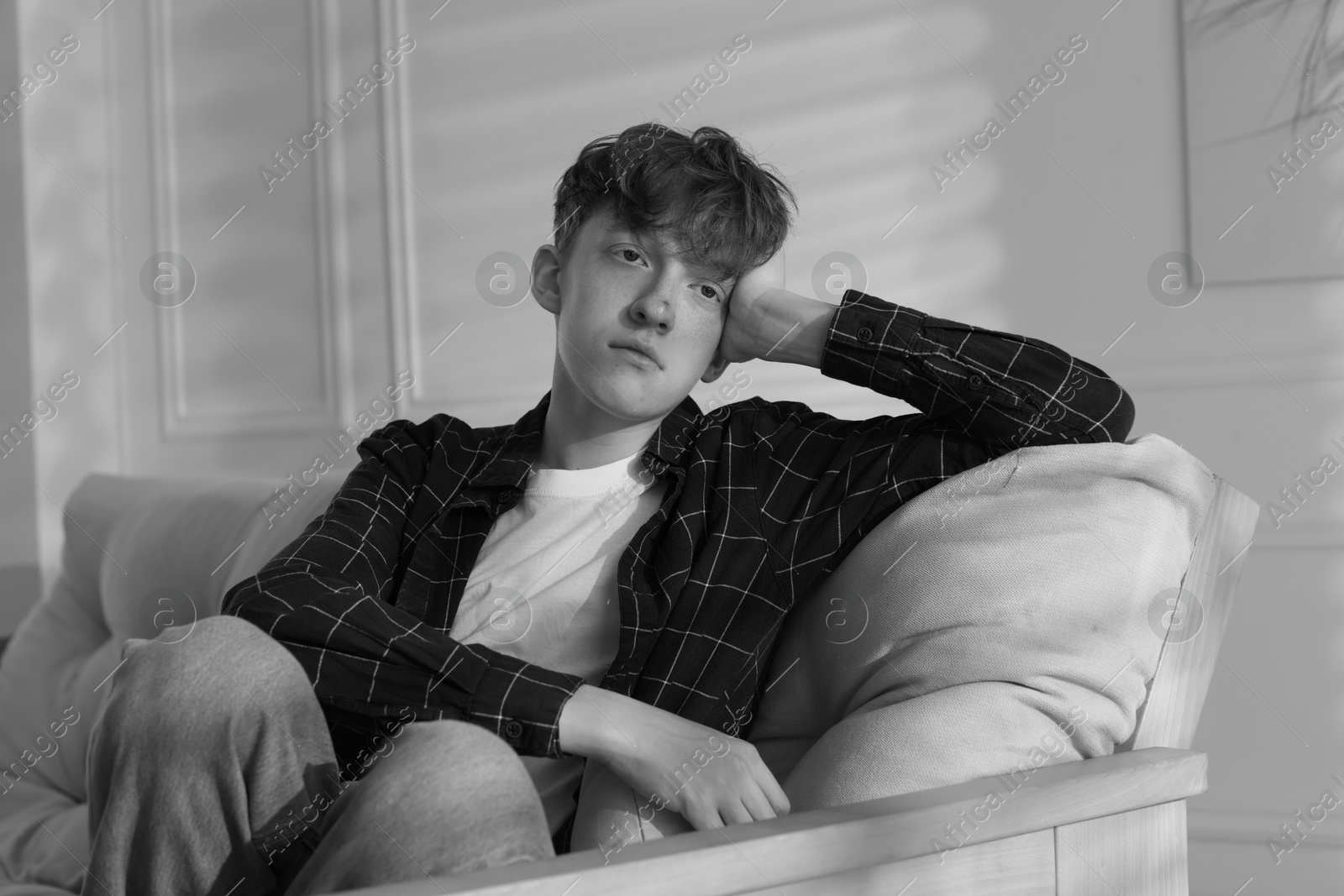 Teen problems. Depressed teenage boy on sofa at home. Black and white effect Photo of Teen problems. Depressed teenage boy on sofa at home. Black and white effect