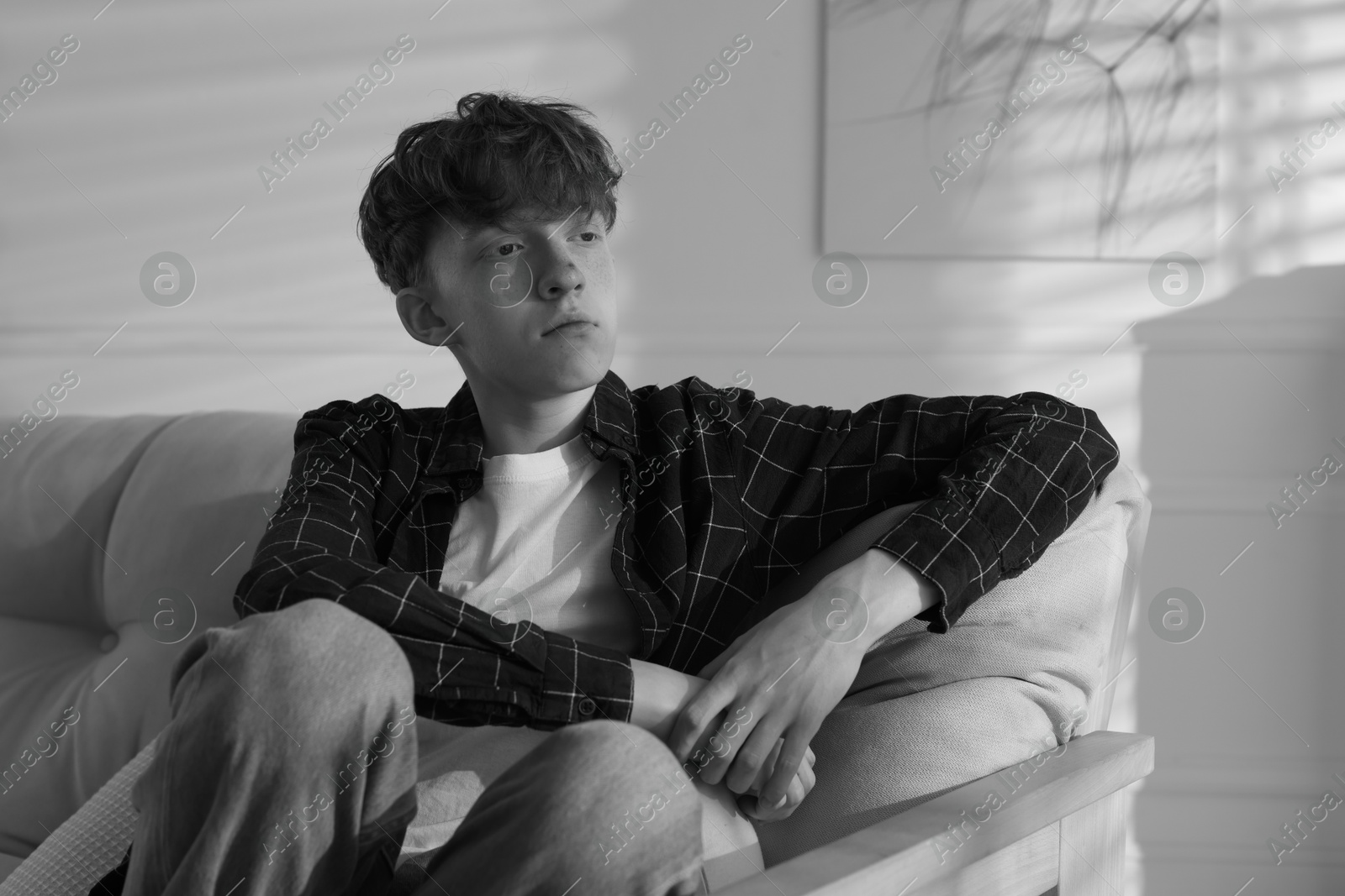 Teen problems. Depressed teenage boy on sofa at home. Black and white effect Photo of Teen problems. Depressed teenage boy on sofa at home. Black and white effect