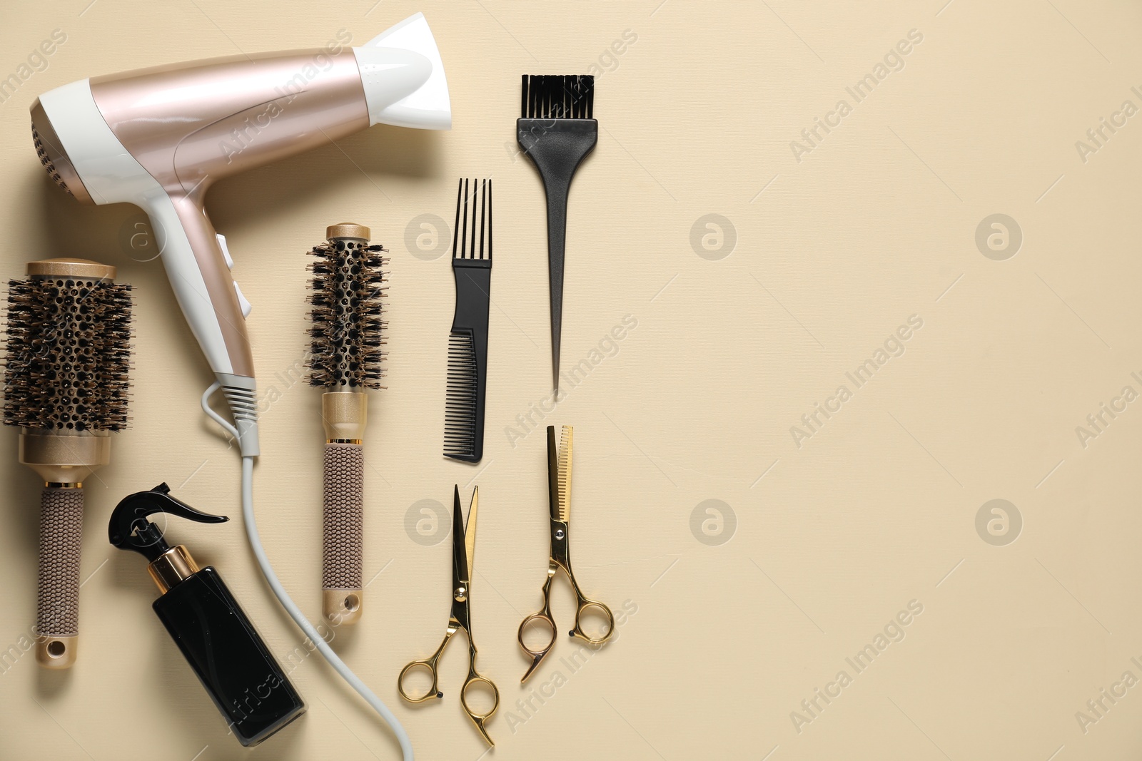 Photo of Round brushes, dryer and other hairdresser's tools on beige background, flat lay. Space for text