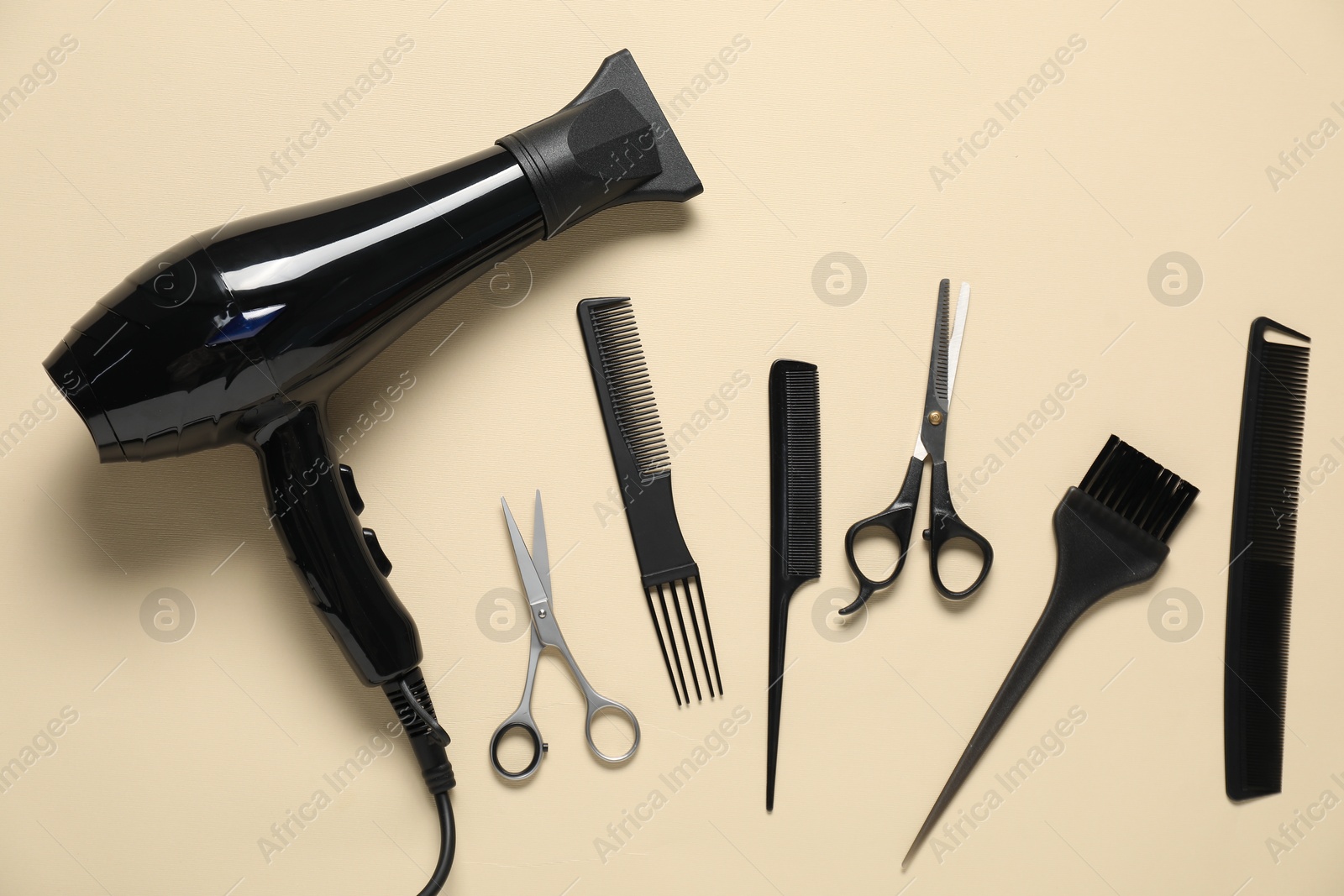 Photo of Combs, dryer and other hairdresser's tools on beige background, flat lay