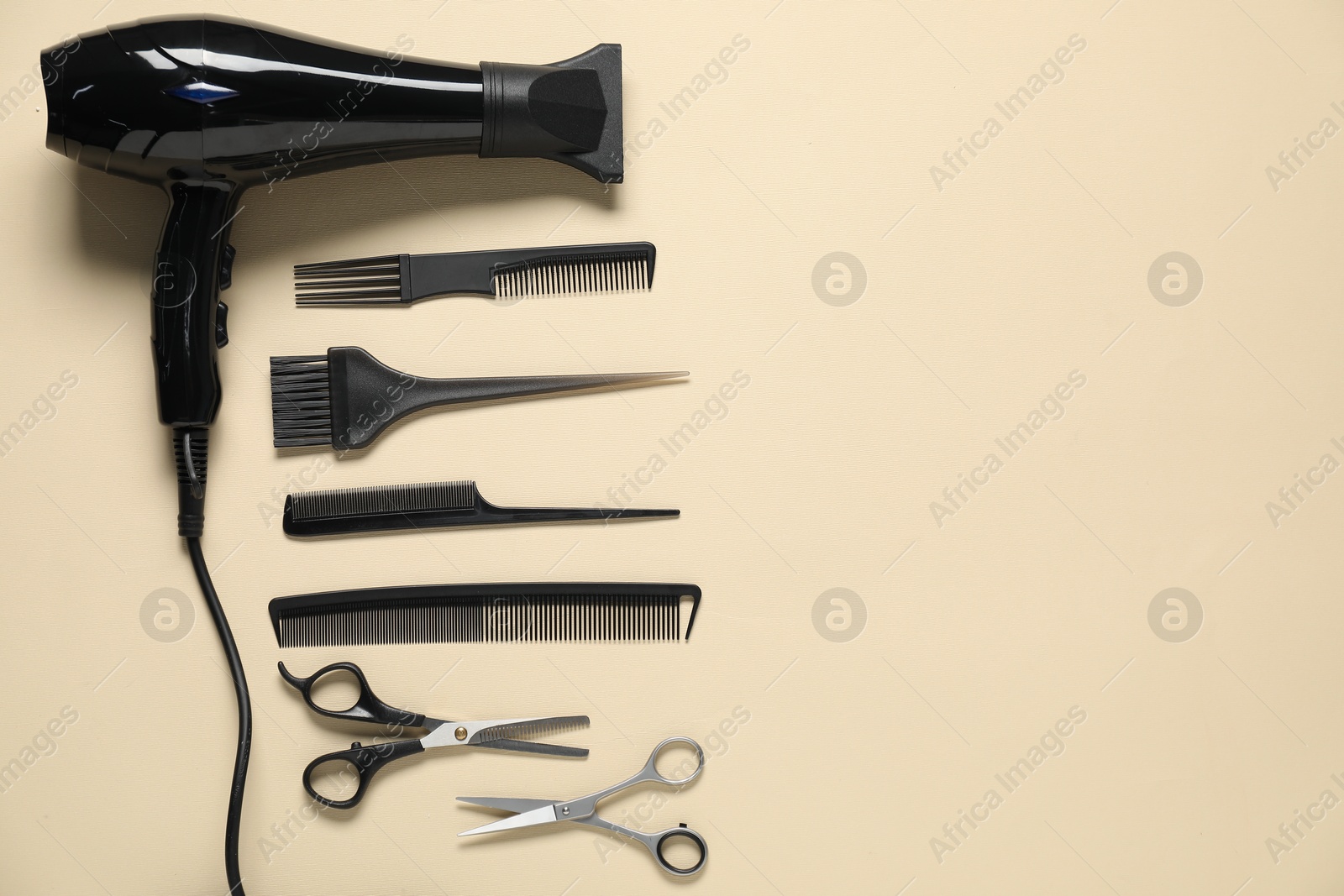 Combs, dryer and other hairdresser's tools on beige background, flat lay. Space for text Photo of Combs, dryer and other hairdresser's tools on beige background, flat lay. Space for text