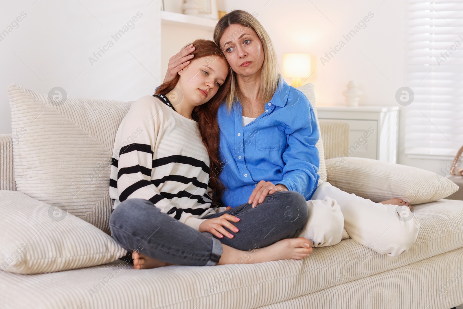 Mother consoling her upset daughter on sofa at home Photo of Mother consoling her upset daughter on sofa at home