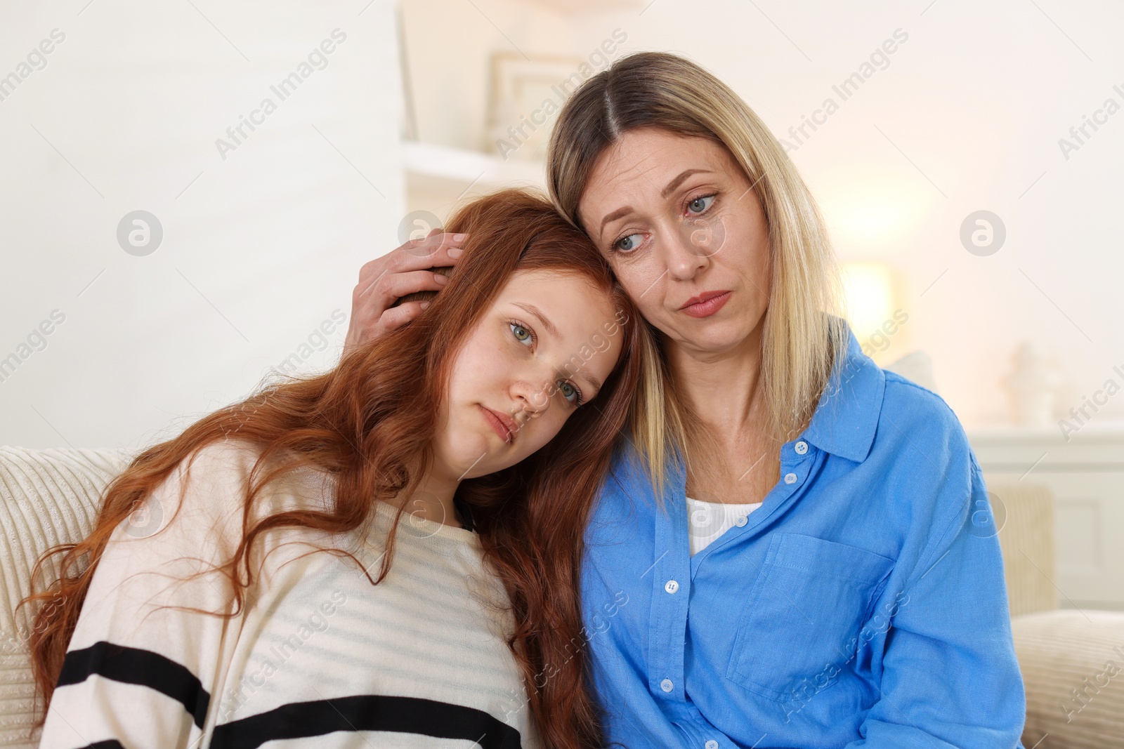 Mother consoling her upset daughter on sofa at home Photo of Mother consoling her upset daughter on sofa at home
