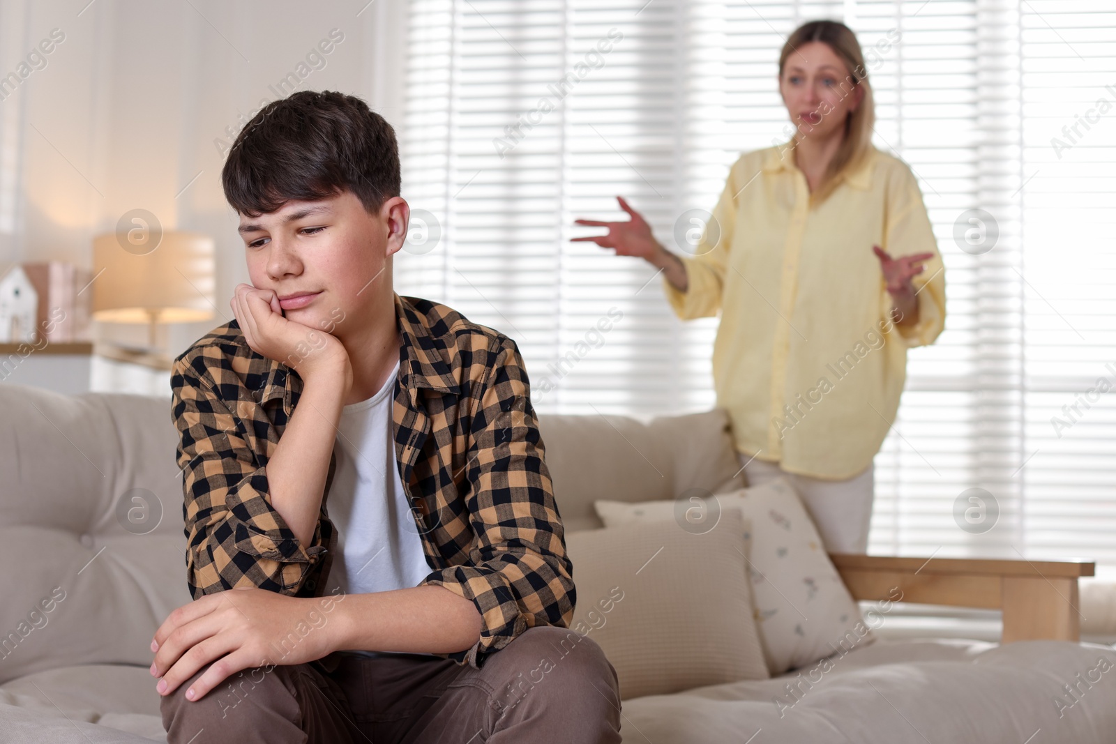 Mother scolding her teenage son at home, selective focus Photo of Mother scolding her teenage son at home, selective focus