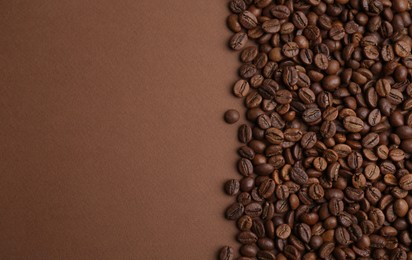 Photo of Aromatic coffee beans on brown background, top view. Space for text