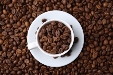 Photo of Cup and saucer on coffee beans, top view