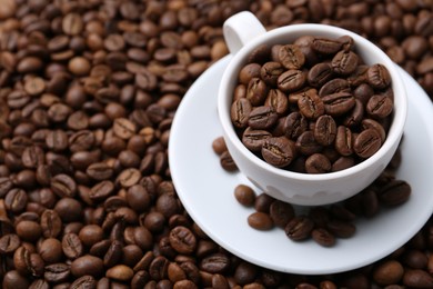 Photo of Cup and saucer on coffee beans, closeup. Space for text