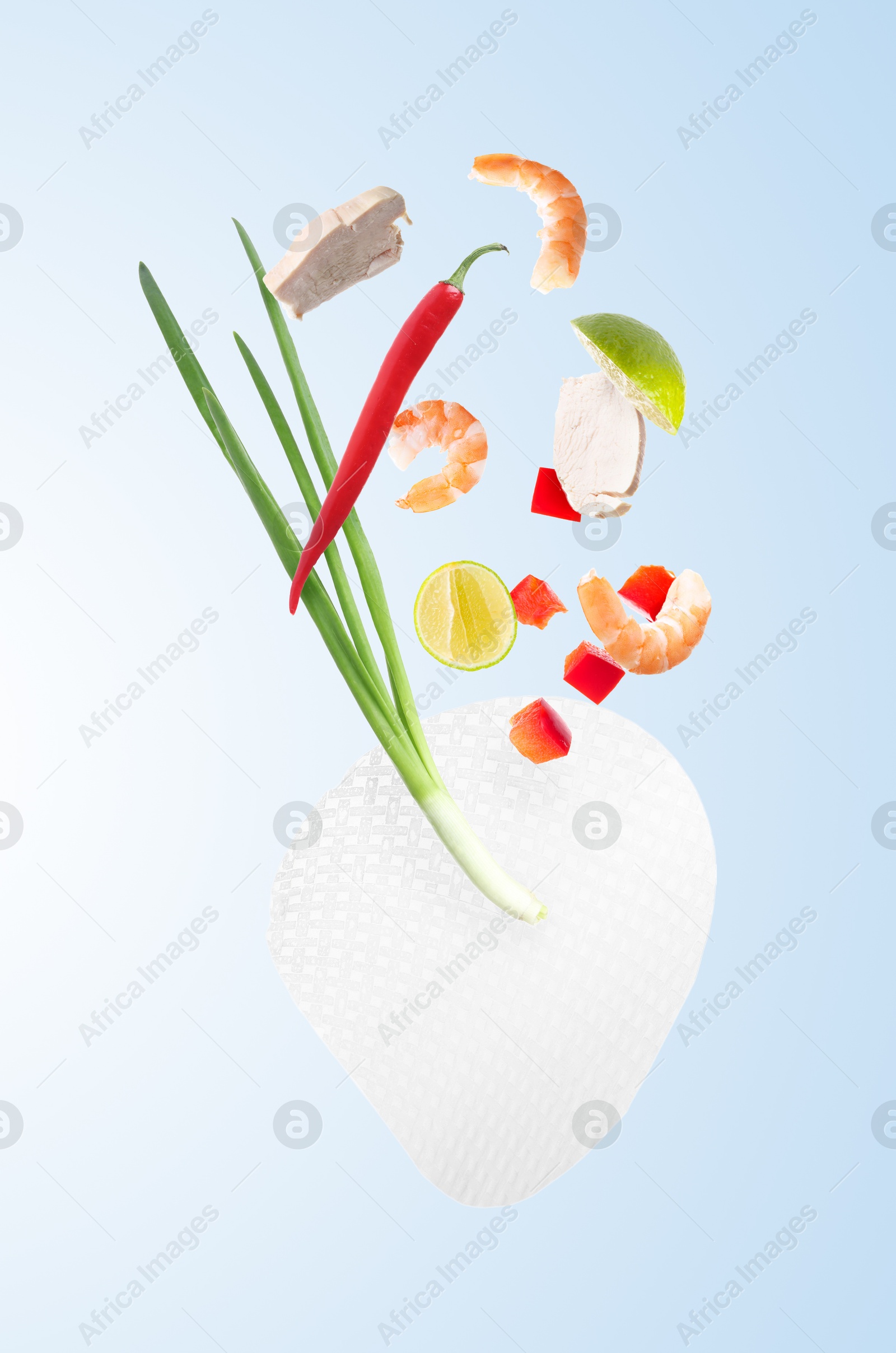 Rice paper and different ingredients falling on light blue gradient background Image of Rice paper and different ingredients falling on light blue gradient background