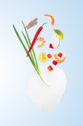 Image of Rice paper and different ingredients falling on light blue gradient background