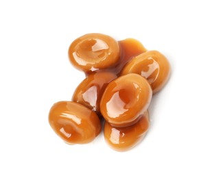Photo of Tasty sweet candies and caramel sauce isolated on white, top view