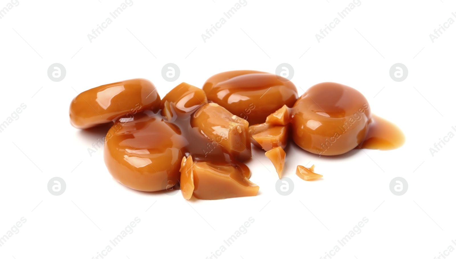 Tasty sweet candies and caramel sauce isolated on white Photo of Tasty sweet candies and caramel sauce isolated on white