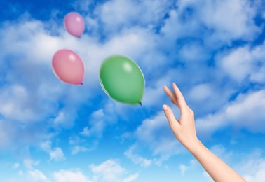 Image of Woman let go balloons out of her hand into sky, closeup. Freedom concept