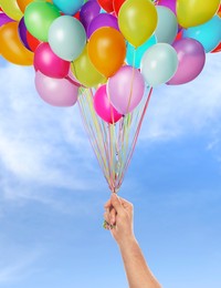 Image of Man is about to let bunch of balloons out of his hand into sky, closeup. Freedom concept