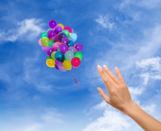 Image of Woman let go bunch of balloons out of her hand into sky, closeup. Freedom concept