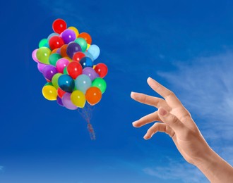 Image of Woman let go bunch of balloons out of her hand into sky, closeup. Freedom concept