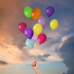 Image of Man is about to let bunch of balloons out of his hand into sky, closeup. Freedom concept