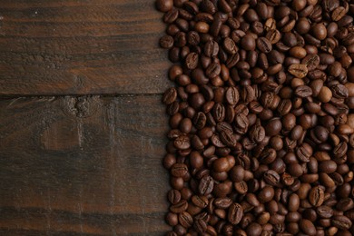 Photo of Aromatic coffee beans on wooden table, top view. Space for text